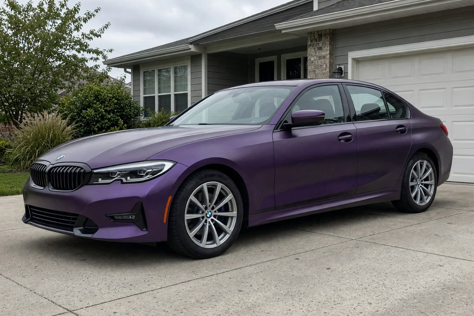 The same white BMW 3 Series in the same driveway, wrapped in Satin Midnight Purple.