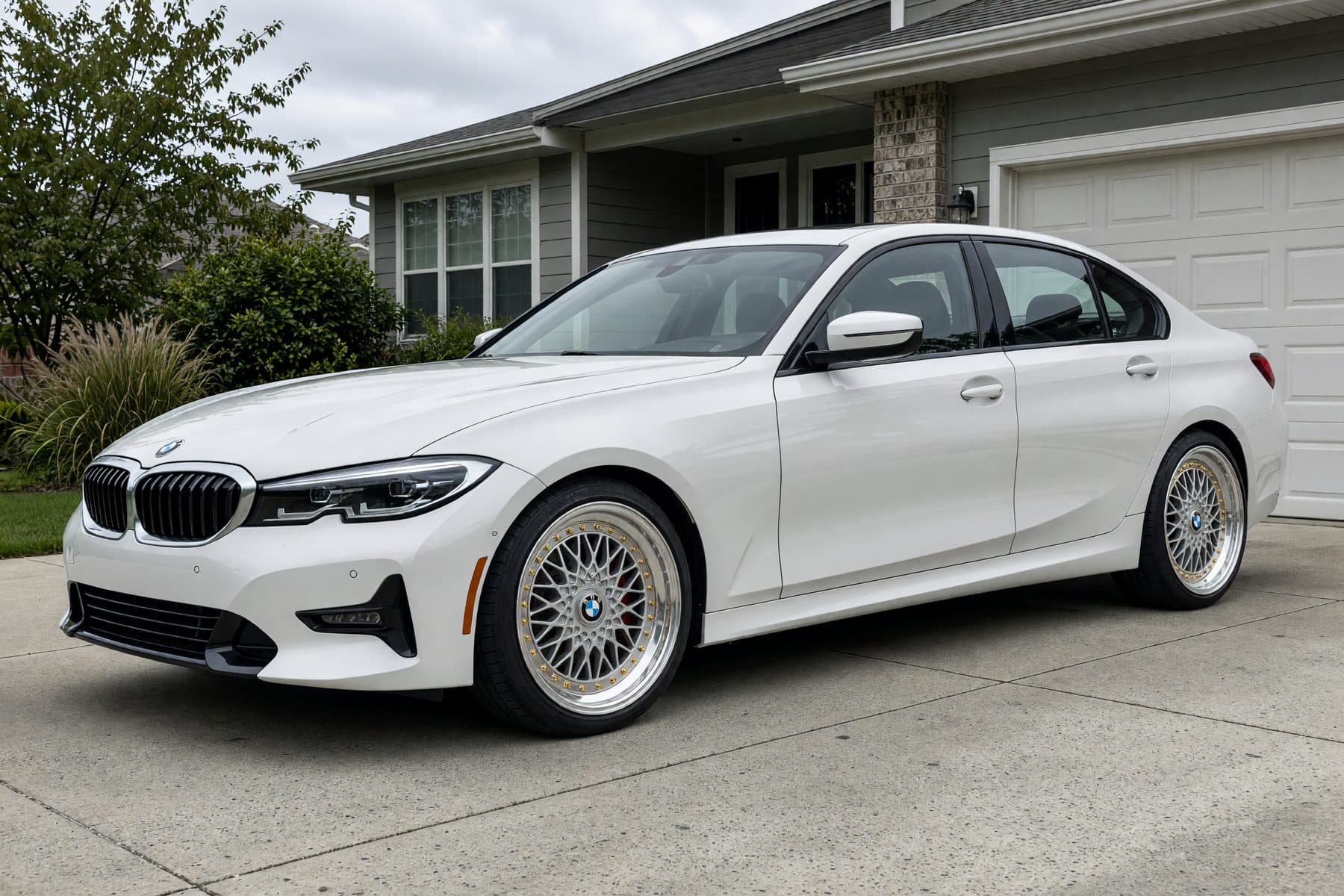 The same white BMW 3 Series in the same driveway, wearing the Heritage Mesh wheel (18" · polished silver · classic mesh).