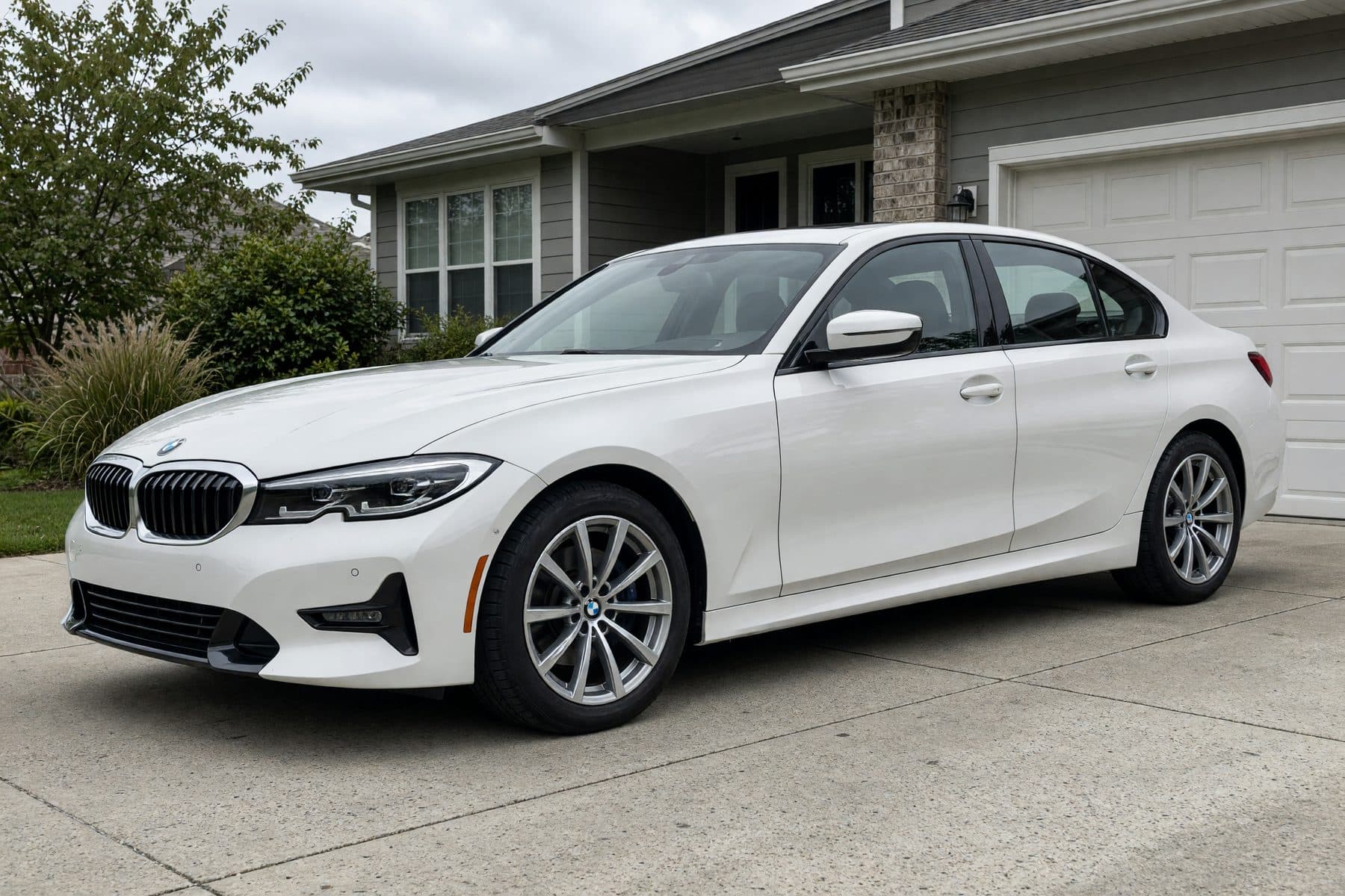 A customer photo of a white BMW 3 Series on its factory silver wheels, parked in a driveway.